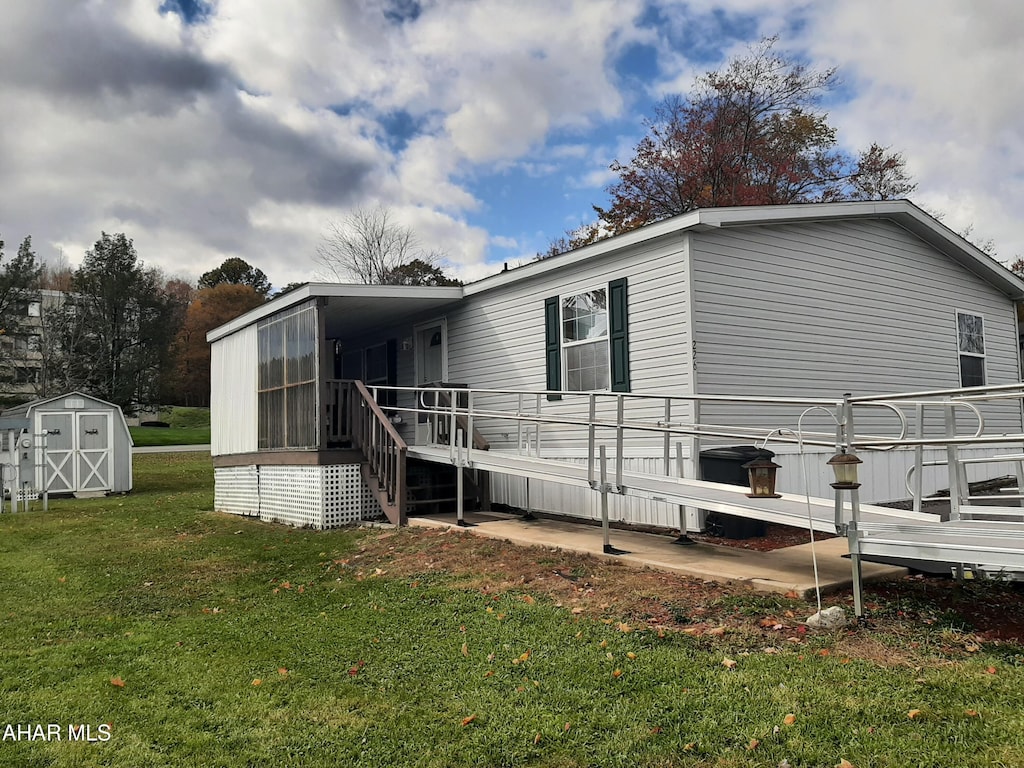 back of property featuring a sunroom, a yard, a storage unit, and a deck