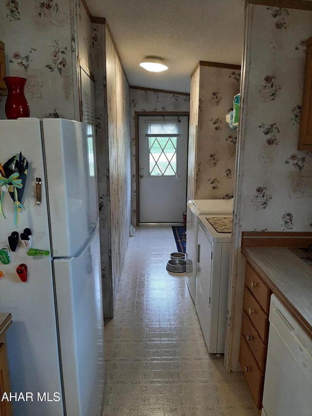 kitchen with a textured ceiling, white appliances, and washer / dryer