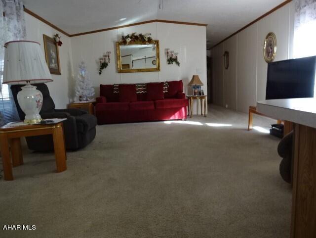 living room featuring crown molding, carpet, and vaulted ceiling