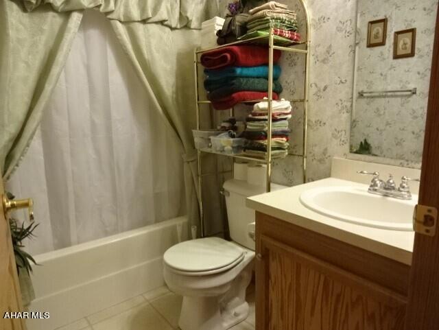 full bathroom with tile patterned flooring, vanity, shower / bath combo, and toilet