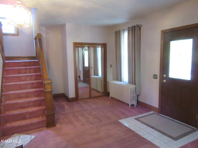 carpeted foyer featuring radiator, plenty of natural light, and an inviting chandelier