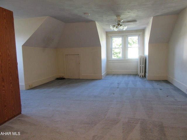 additional living space featuring radiator heating unit, light colored carpet, ceiling fan, and lofted ceiling