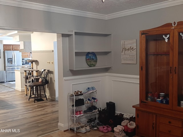 interior space featuring a textured ceiling, crown molding, wood-type flooring, and stainless steel refrigerator with ice dispenser