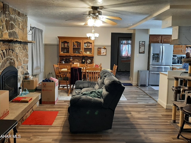 living room with a textured ceiling, light hardwood / wood-style floors, a wood stove, and ceiling fan