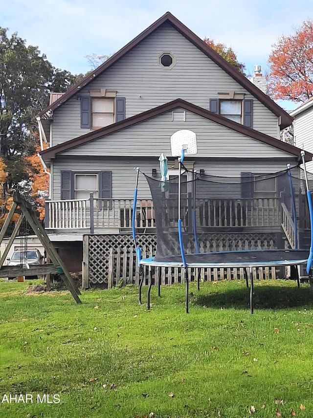 back of property featuring a yard and a trampoline