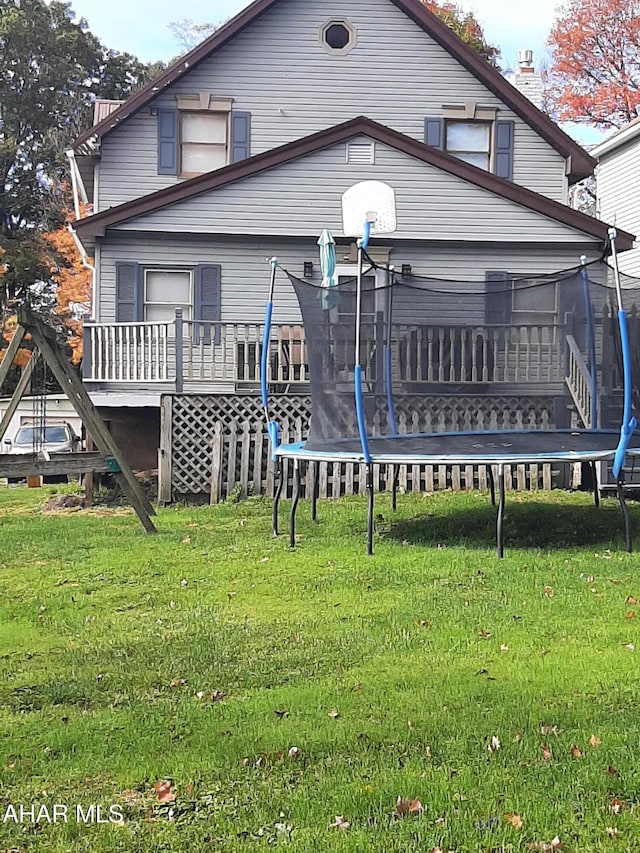 rear view of house featuring a yard and a trampoline