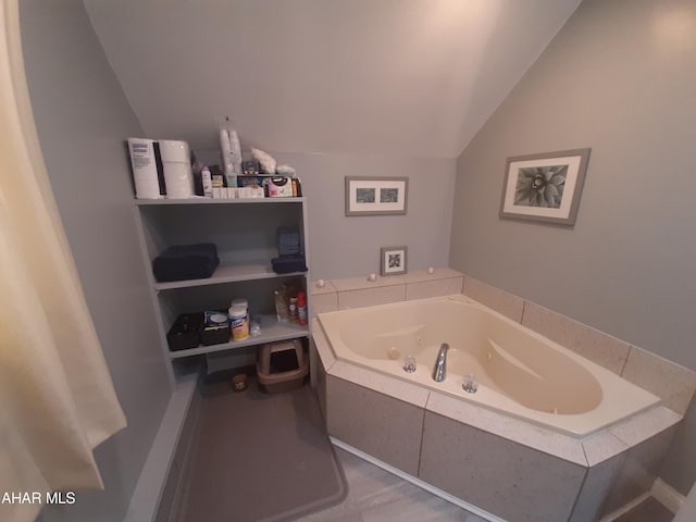 bathroom with tiled bath and vaulted ceiling