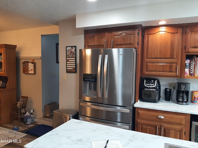 kitchen featuring stainless steel fridge, wood-type flooring, and a textured ceiling