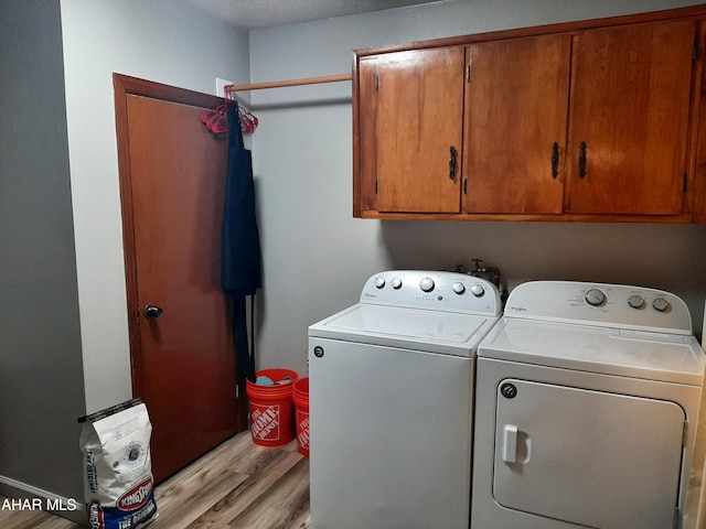 clothes washing area featuring cabinets, separate washer and dryer, a textured ceiling, and light hardwood / wood-style flooring