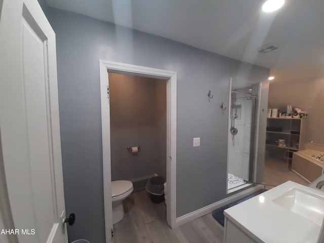 bathroom featuring wood-type flooring, vanity, toilet, and a shower with door