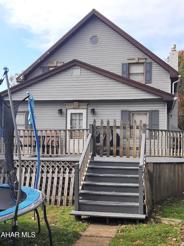 back of property featuring a deck and a trampoline