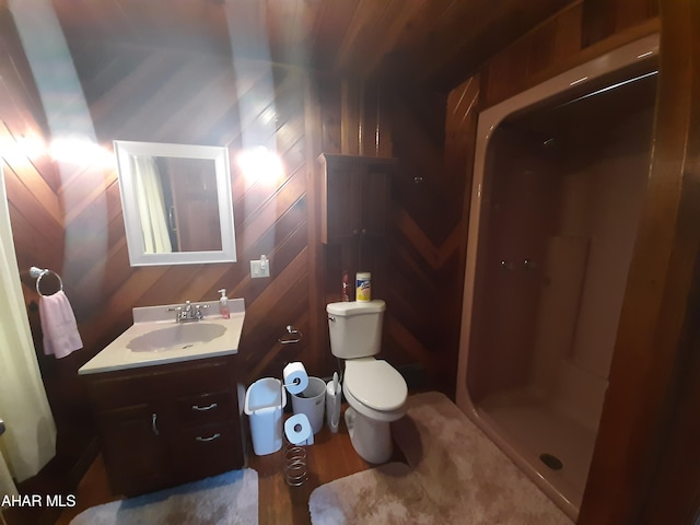 bathroom featuring vanity, a shower, wooden walls, hardwood / wood-style flooring, and toilet