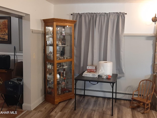 sitting room featuring dark wood-type flooring and a baseboard heating unit