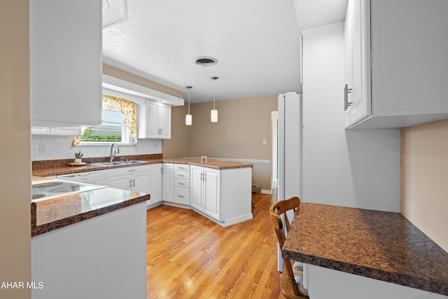 409 Tree Ln, Duncansville, PA 16635 - kitchen with a sink, a peninsula, dark countertops, light wood finished floors, and white cabinetry