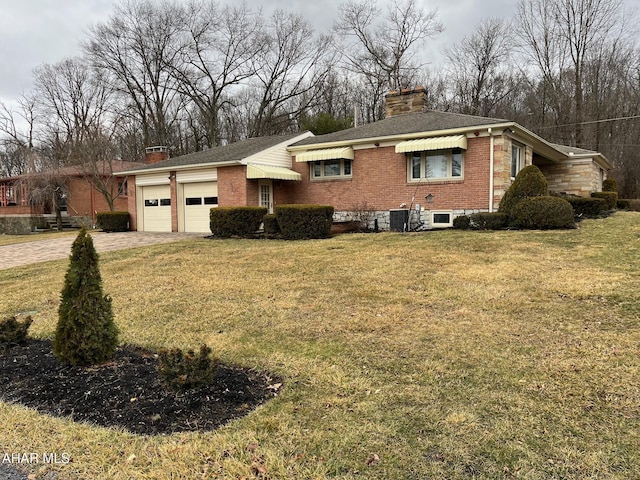 view of front of house with an attached garage, brick siding, driveway, a chimney, and a front yard