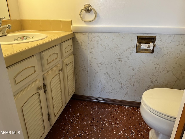 bathroom with baseboards, a wainscoted wall, vanity, and toilet