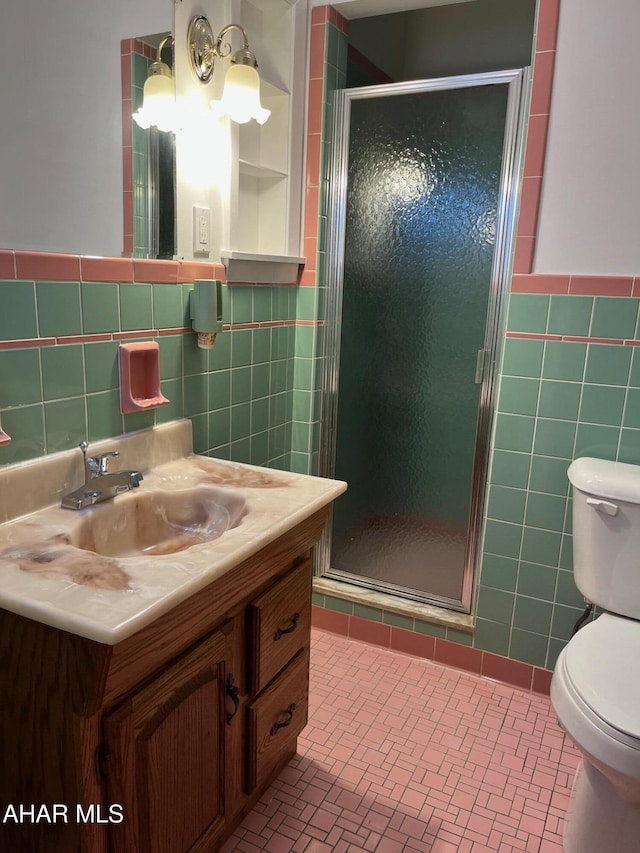 bathroom featuring toilet, a stall shower, tile walls, and vanity