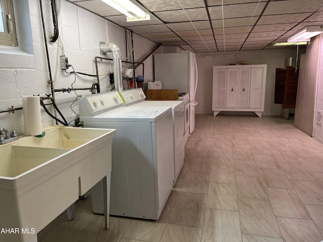 washroom featuring concrete block wall, laundry area, a sink, and independent washer and dryer