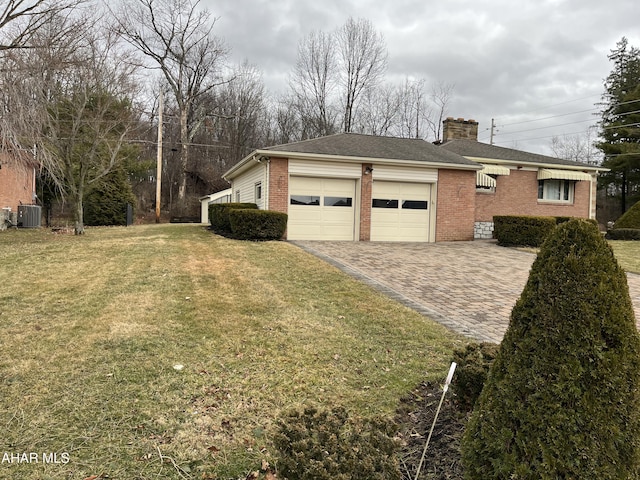 view of property exterior featuring a garage, a chimney, decorative driveway, a yard, and brick siding