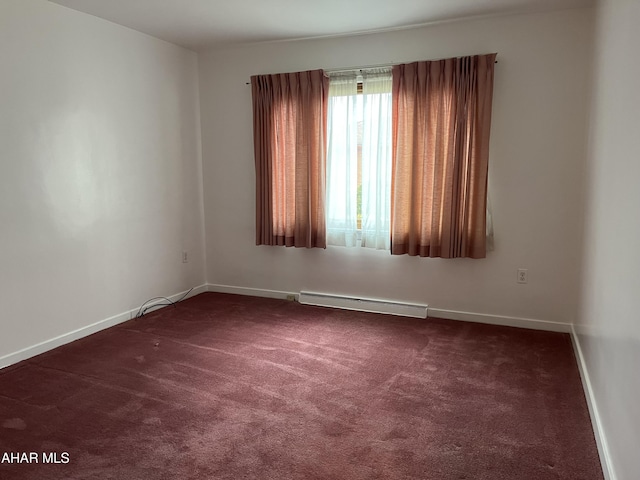 carpeted spare room featuring a baseboard heating unit and baseboards