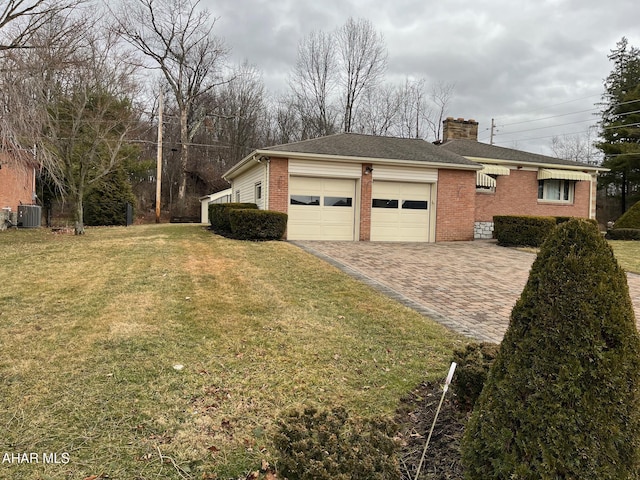 view of home's exterior featuring an attached garage, brick siding, a yard, decorative driveway, and a chimney