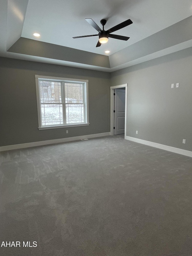 empty room featuring carpet, ceiling fan, and a tray ceiling