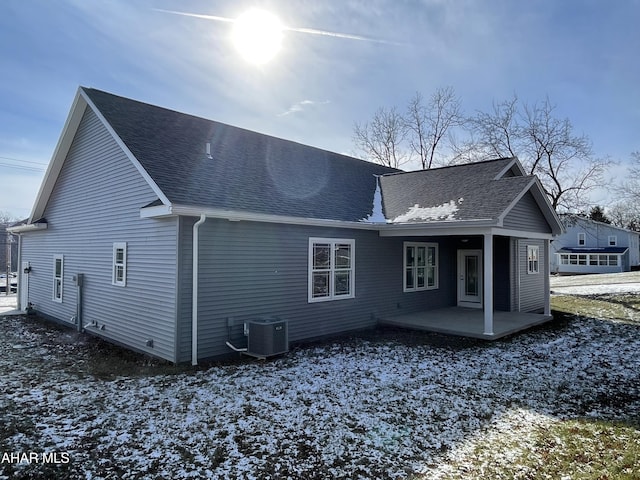 snow covered back of property with a patio and cooling unit