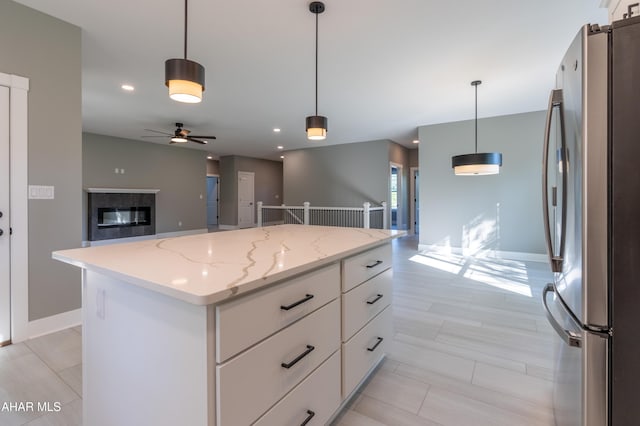 kitchen featuring stainless steel fridge, a center island, white cabinets, and hanging light fixtures