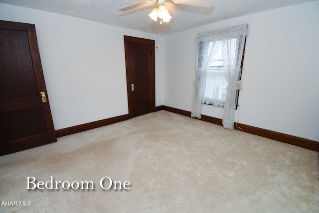 carpeted spare room with a textured ceiling and ceiling fan