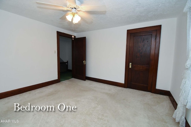 spare room with light carpet, ceiling fan, and a textured ceiling