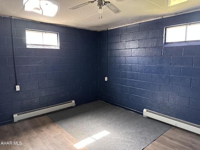 basement with plenty of natural light, wood-type flooring, and baseboard heating