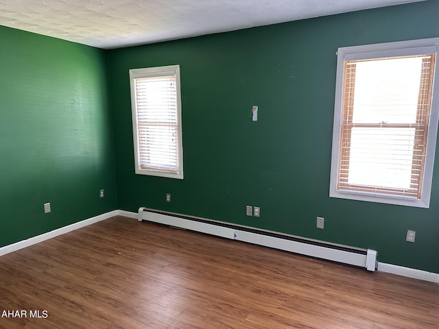 empty room with hardwood / wood-style floors, a baseboard radiator, and a textured ceiling