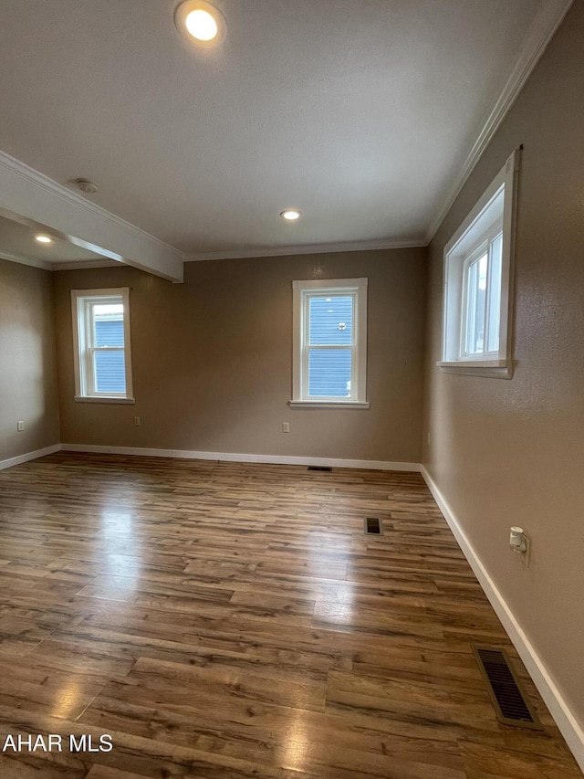 spare room featuring plenty of natural light, dark hardwood / wood-style flooring, and crown molding