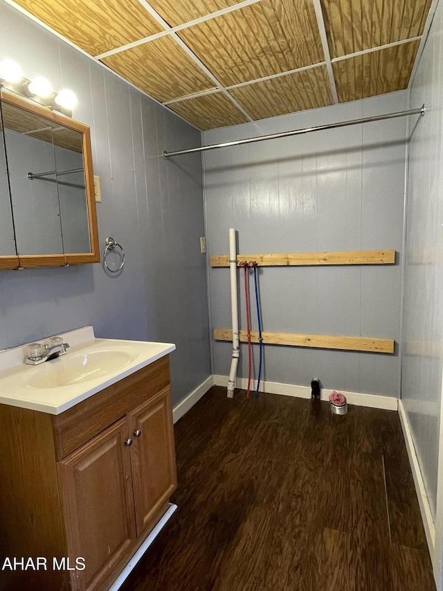 bathroom with wooden walls, vanity, and wood-type flooring