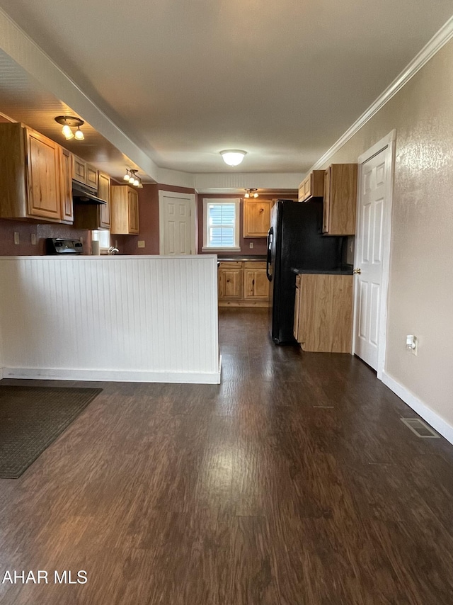 kitchen featuring black fridge, ornamental molding, and dark wood-type flooring