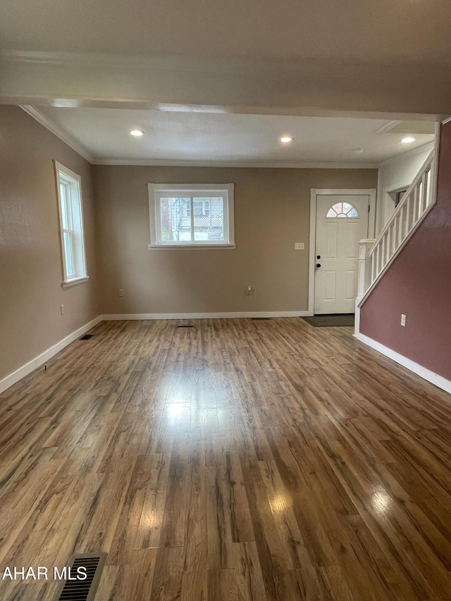 unfurnished living room featuring dark hardwood / wood-style floors, plenty of natural light, and crown molding