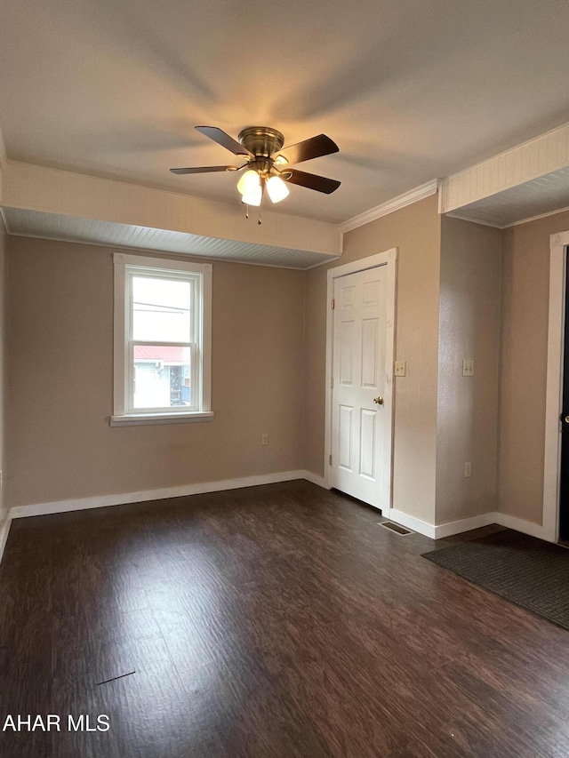 empty room featuring ceiling fan, dark hardwood / wood-style flooring, and ornamental molding