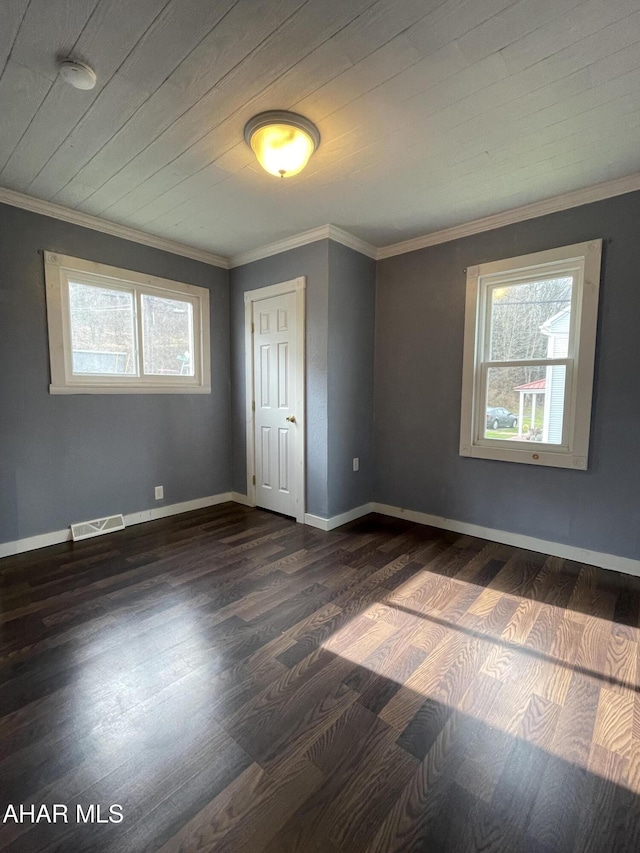 empty room featuring wooden ceiling, dark wood-type flooring, a healthy amount of sunlight, and ornamental molding