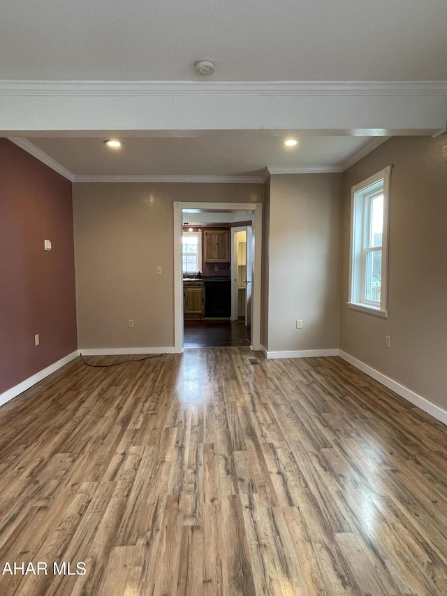 unfurnished living room featuring a wealth of natural light, hardwood / wood-style floors, and ornamental molding