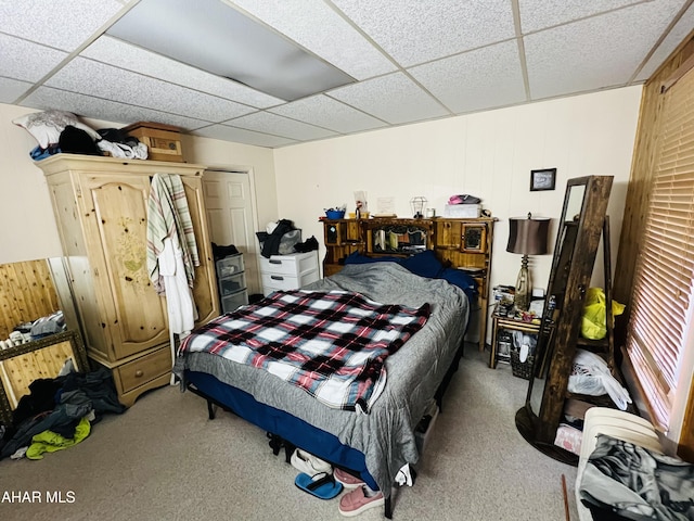 carpeted bedroom featuring a drop ceiling