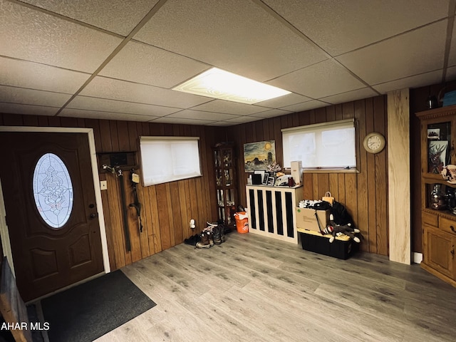 entryway with a drop ceiling, hardwood / wood-style floors, and wood walls