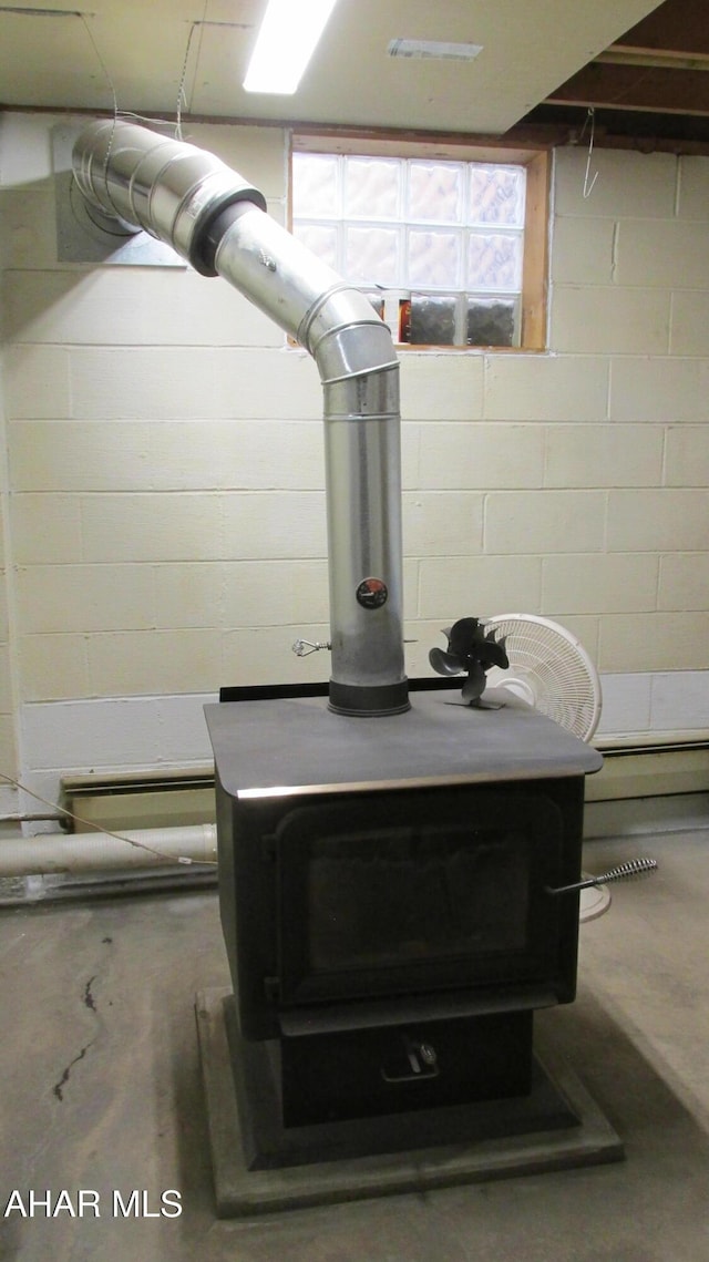 details with concrete flooring, concrete block wall, and a wood stove