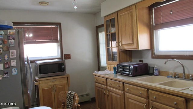 kitchen featuring appliances with stainless steel finishes, brown cabinets, light countertops, and a sink