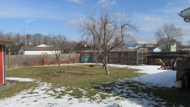 yard layered in snow featuring a fenced backyard and a residential view