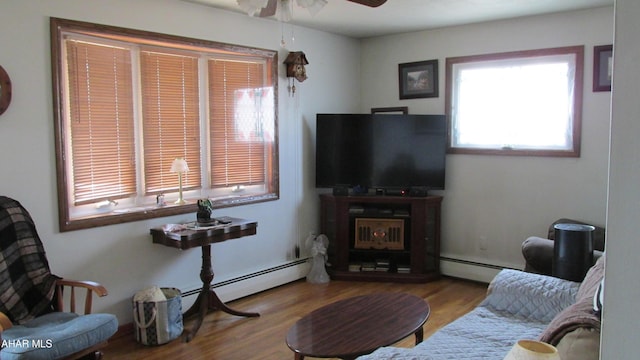 living area with a ceiling fan, light wood finished floors, and baseboard heating