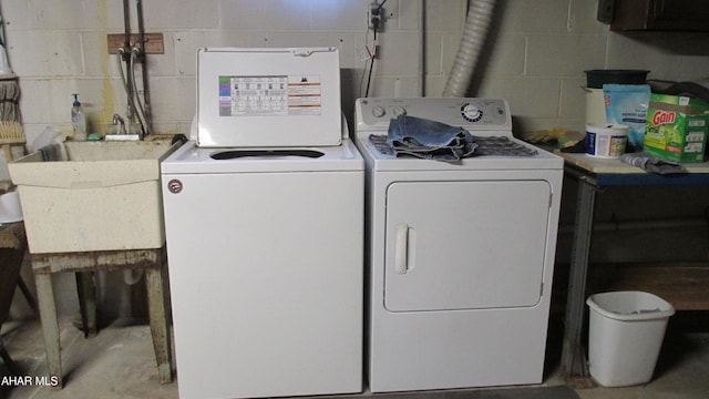 laundry area featuring washing machine and dryer, laundry area, a sink, and concrete block wall