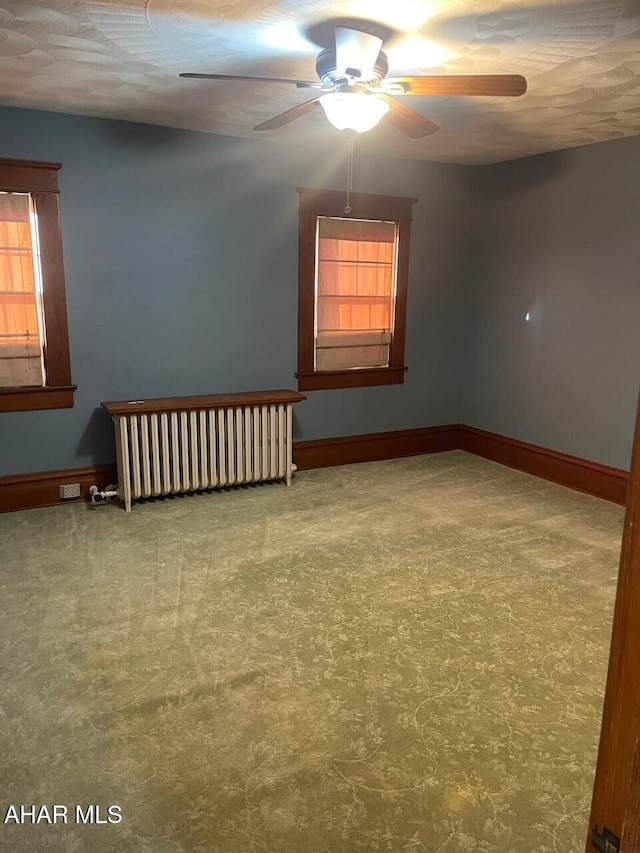 unfurnished room with ceiling fan, radiator heating unit, and carpet floors