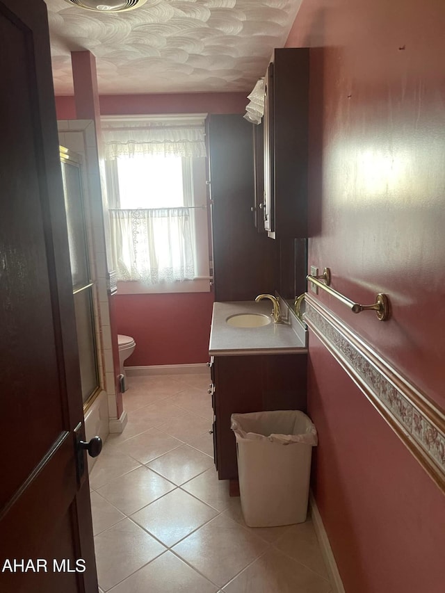 bathroom with tile patterned flooring, vanity, toilet, and walk in shower