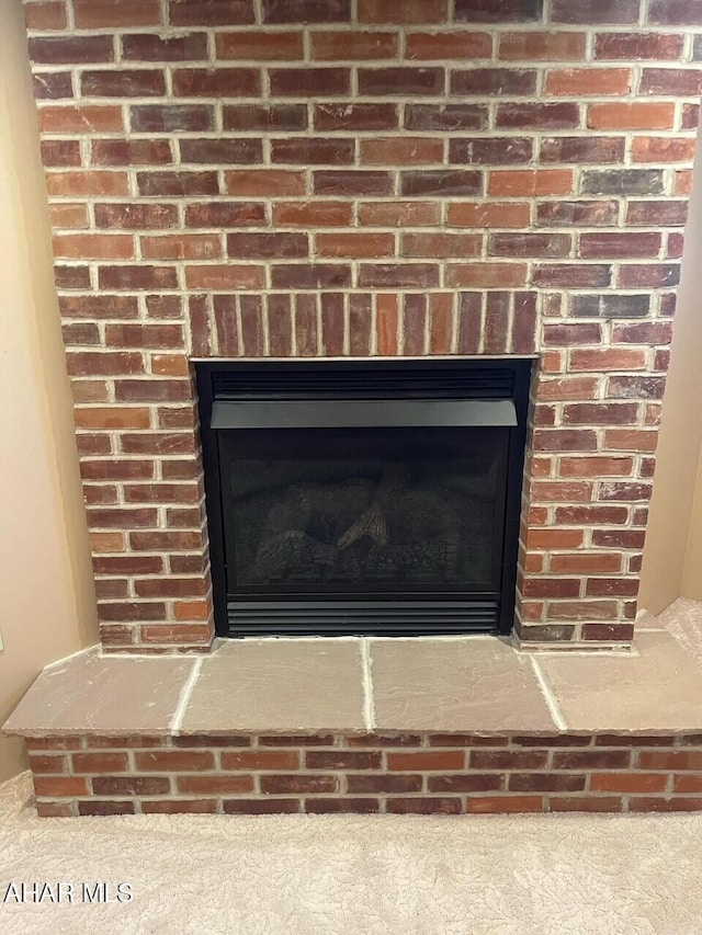 interior details with a brick fireplace and carpet flooring