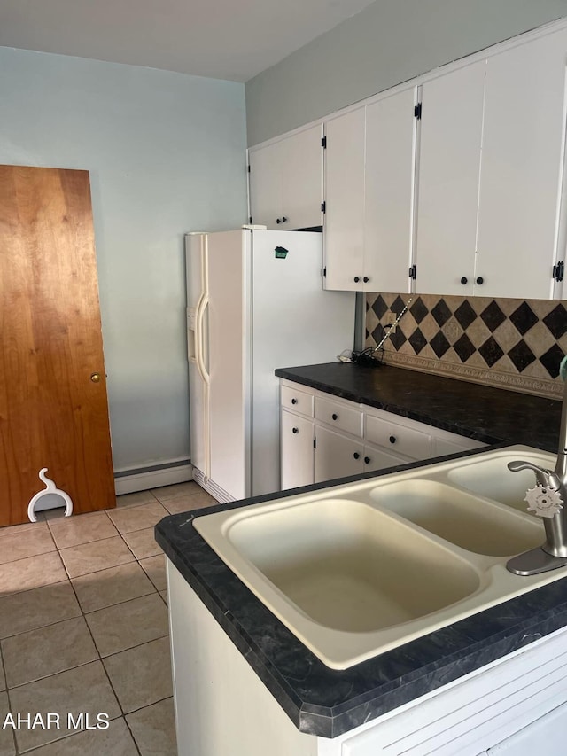 kitchen with light tile patterned floors, sink, tasteful backsplash, white fridge with ice dispenser, and white cabinets